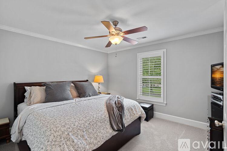 A bedroom with a large bed and a ceiling fan.