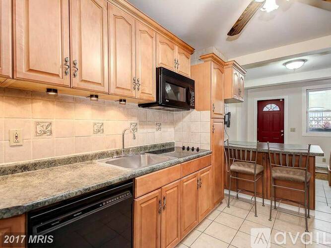 A kitchen with wooden cabinets and a black microwave above the stove.