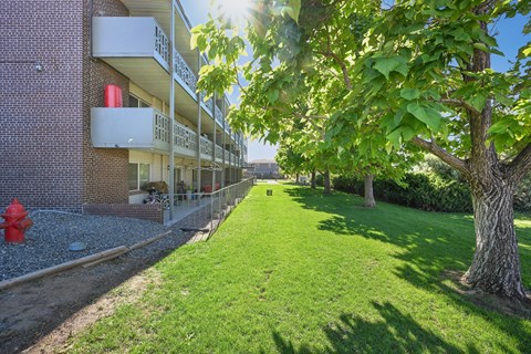 A red fire hydrant sits on a gravel area next to a grassy area in front of a building.