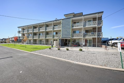 A multi-story apartment building with a parking lot in front.