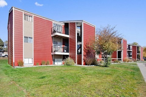 A red apartment building with a balcony on the second floor.