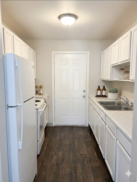 A kitchen with white cabinets and a white door.