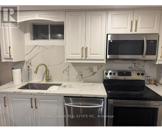A kitchen with a stove, sink, and cabinets.