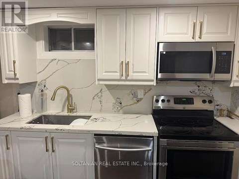 A kitchen with a stove, sink, and cabinets.