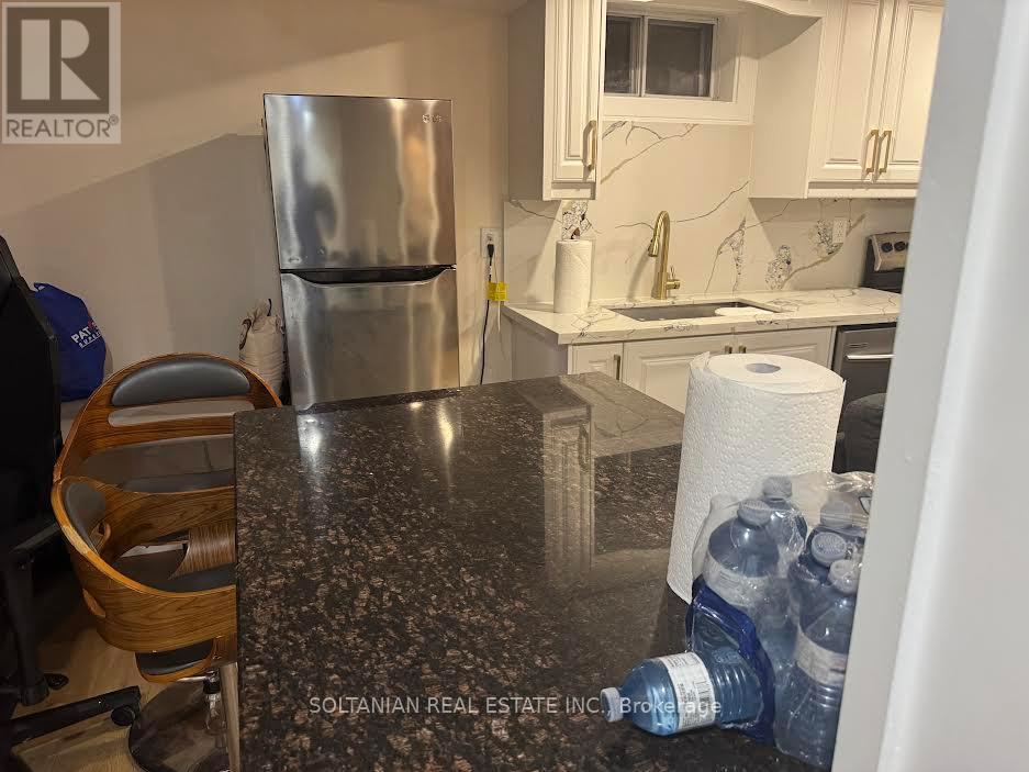 A kitchen with a granite countertop and a stainless steel refrigerator.