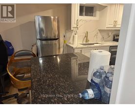 A kitchen with a granite countertop and a stainless steel refrigerator.