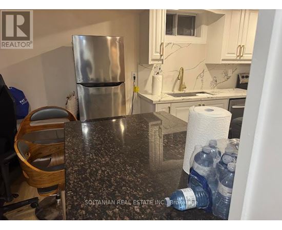 A kitchen with a granite countertop and a stainless steel refrigerator.