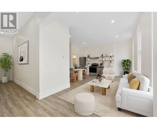 A well-lit, spacious living room with a white sofa, wooden coffee table, and a large painting on the wall.