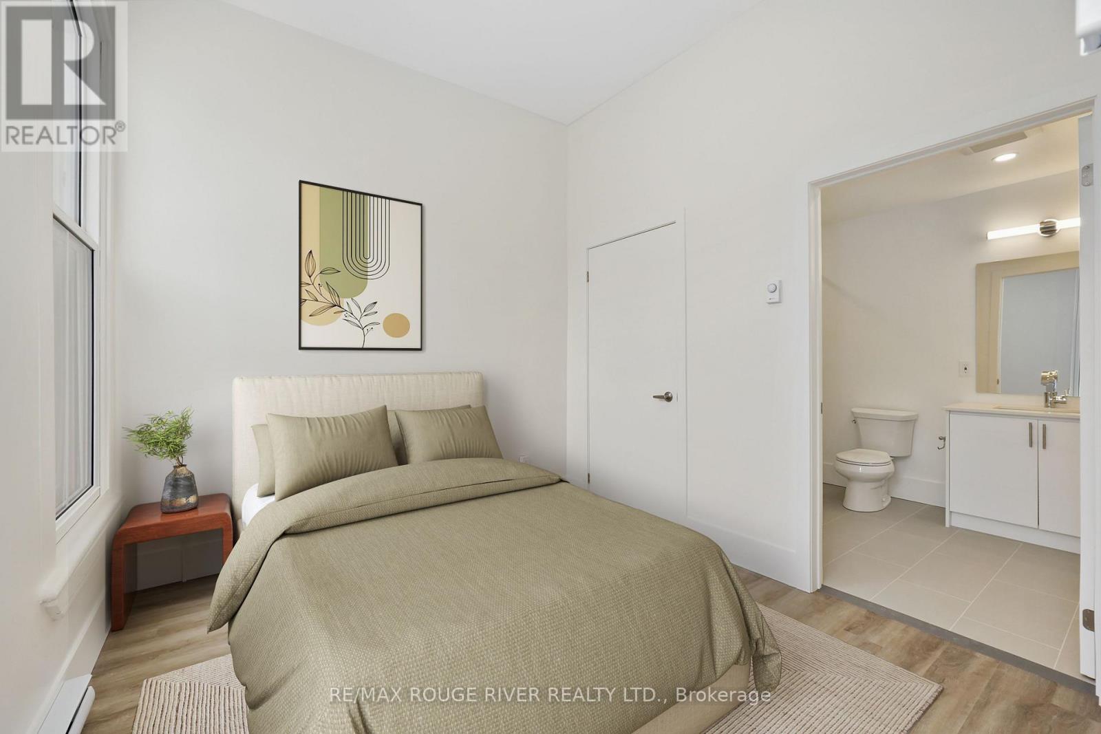A bedroom with a bed, nightstand, and a framed picture on the wall.