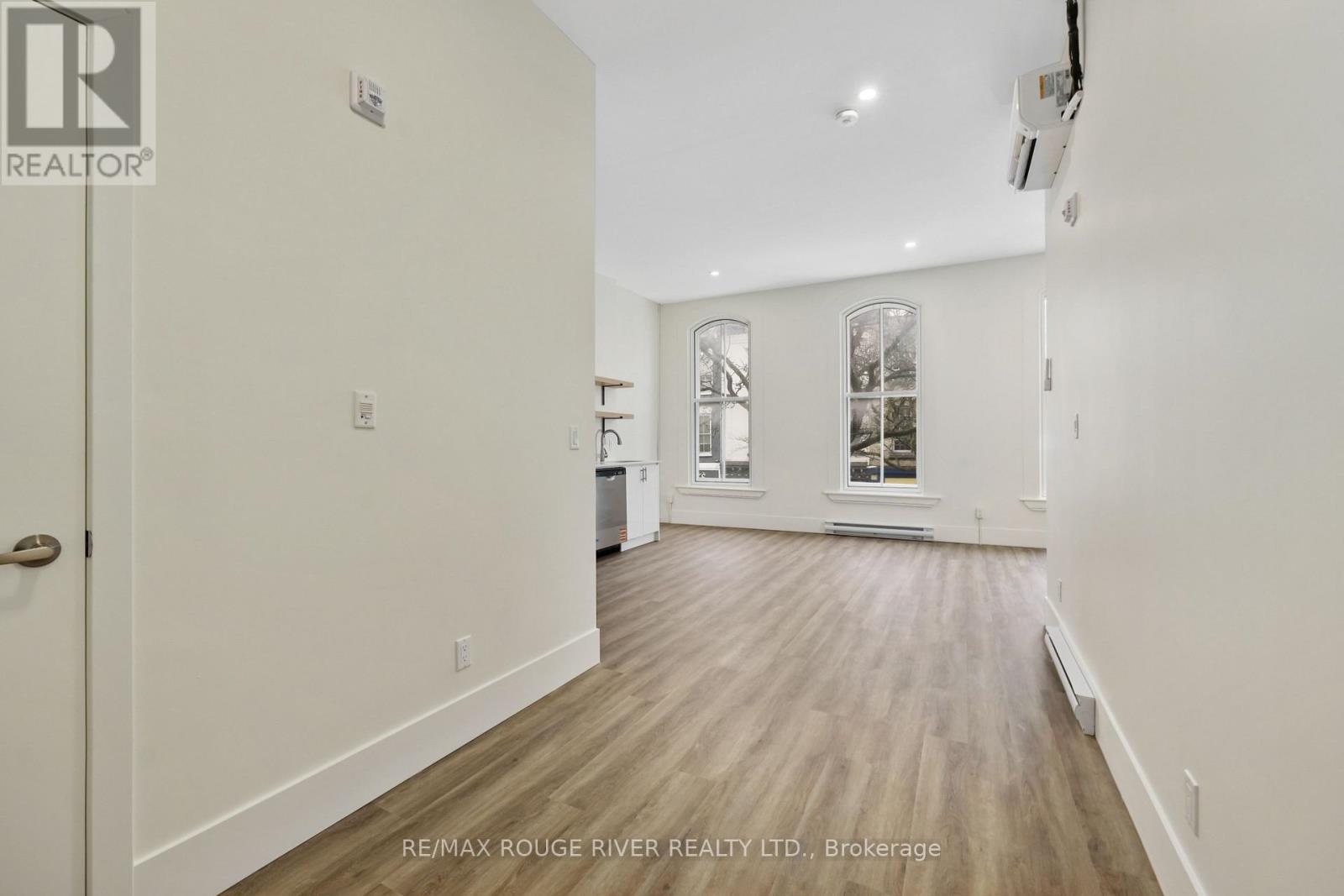 A spacious room with wood flooring and a door on the left.