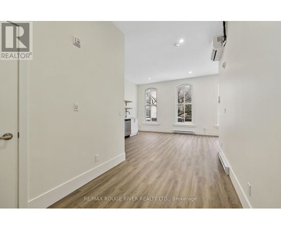 A spacious room with wood flooring and a door on the left.
