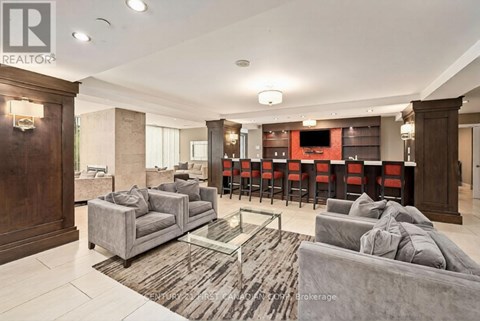 A spacious living room with a grey sofa set and a glass coffee table.