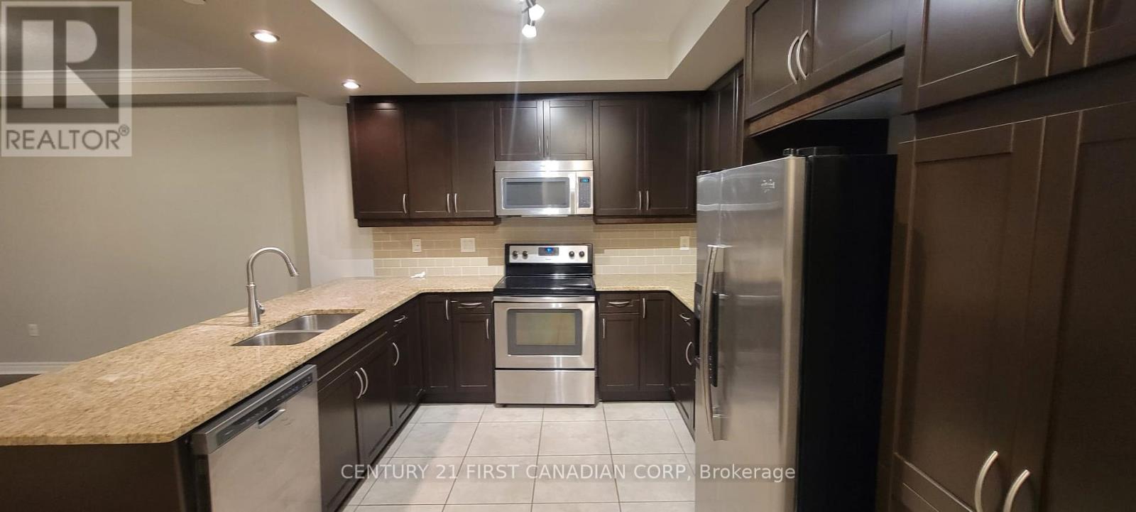 A kitchen with brown cabinets and a stainless steel refrigerator.