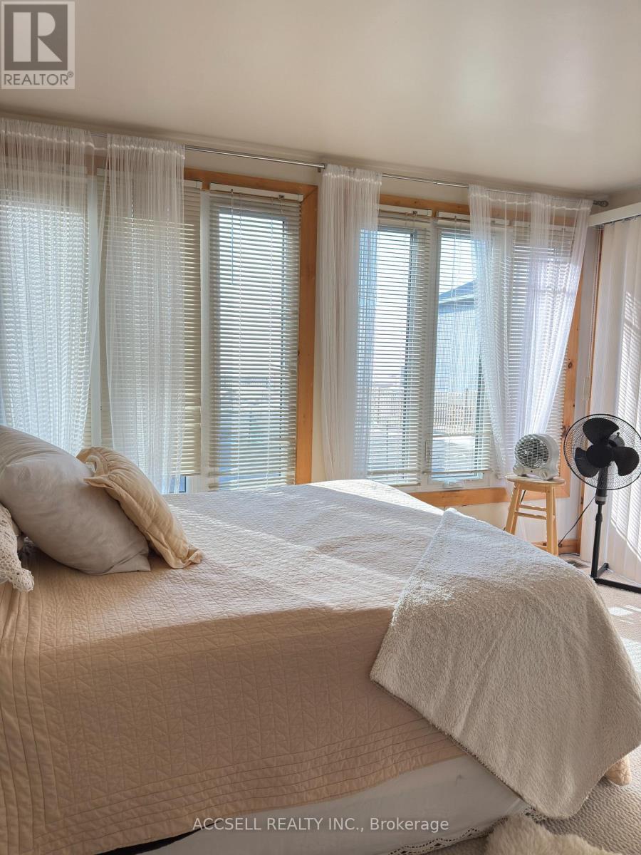 A bedroom with a large bed and a window with curtains.