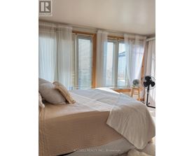 A bedroom with a large bed and a window with curtains.