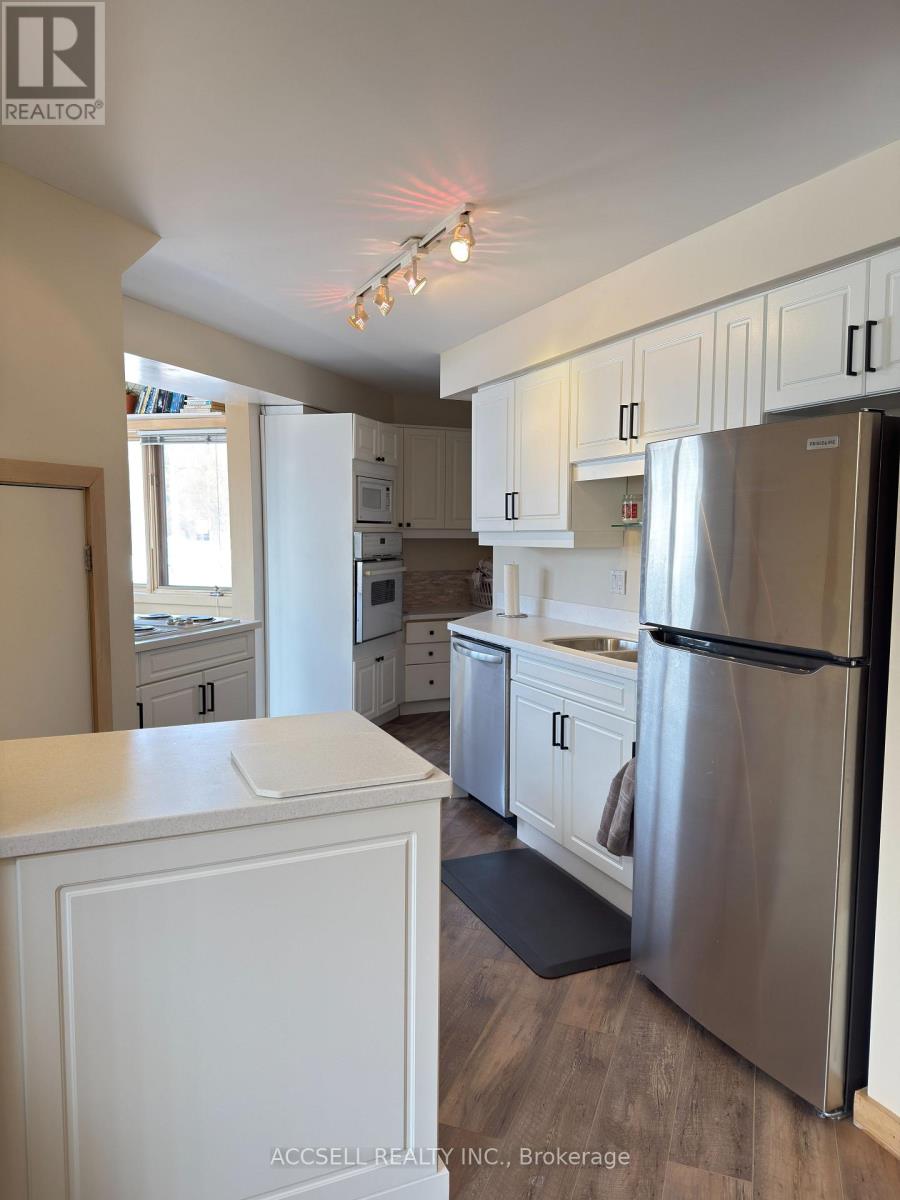 A kitchen with white cabinets and a stainless steel refrigerator.