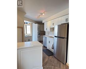 A kitchen with white cabinets and a stainless steel refrigerator.