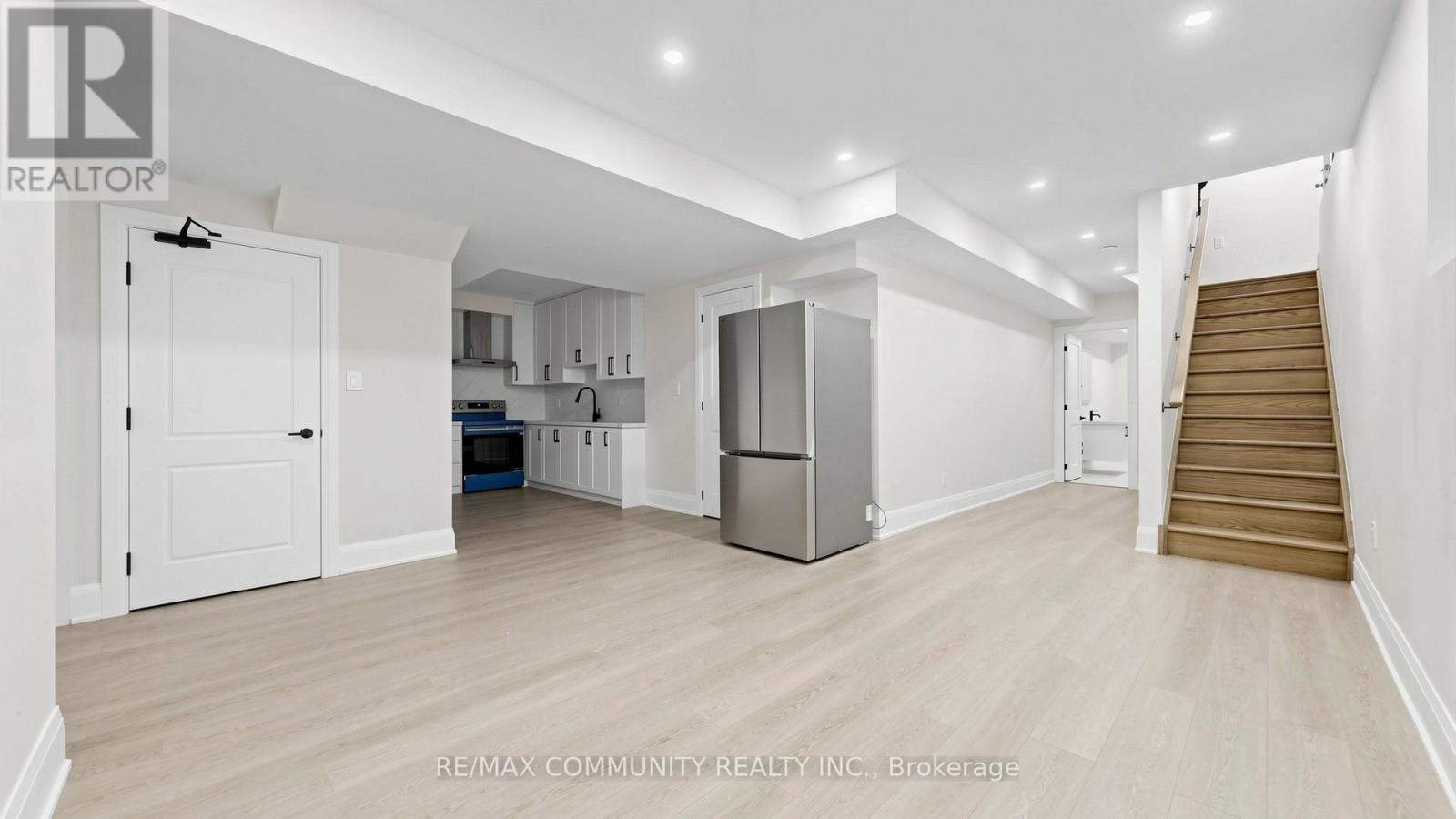 A spacious kitchen with white cabinets and a refrigerator.