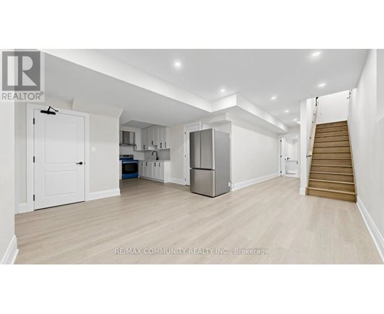 A spacious kitchen with white cabinets and a refrigerator.