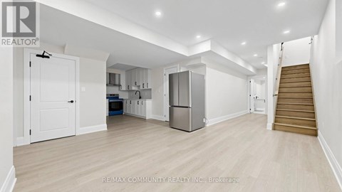 A spacious kitchen with white cabinets and a refrigerator.