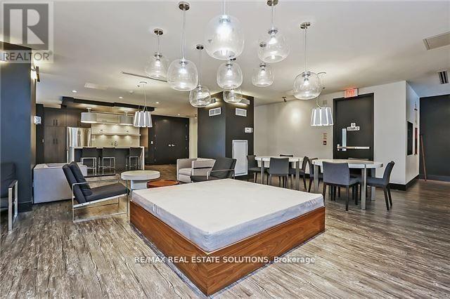 A bedroom with a bed in the center and a dining area in the background.