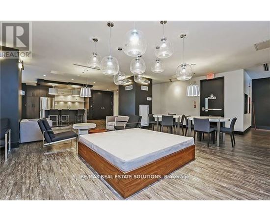 A bedroom with a bed in the center and a dining area in the background.