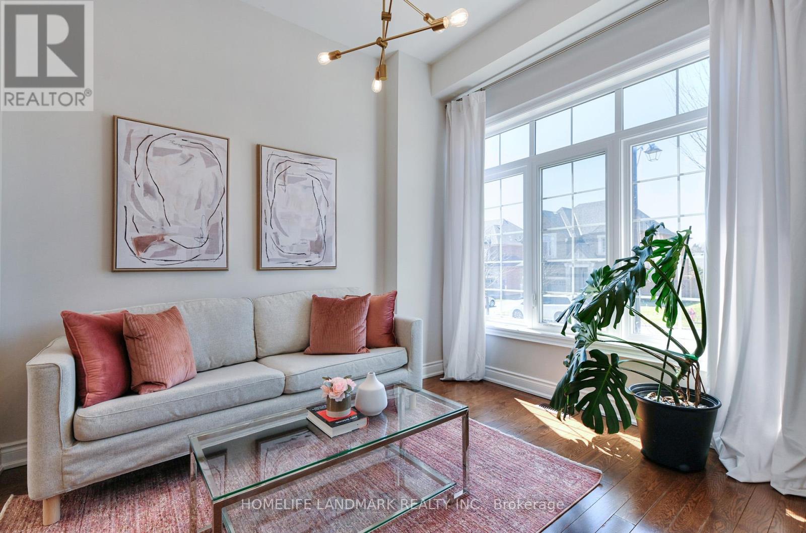 A living room with a grey couch, a glass coffee table, and two framed artworks on the wall.