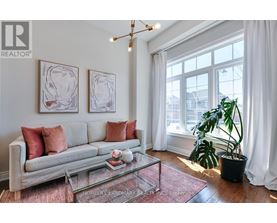 A living room with a grey couch, a glass coffee table, and two framed artworks on the wall.