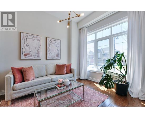 A living room with a grey couch, a glass coffee table, and two framed artworks on the wall.