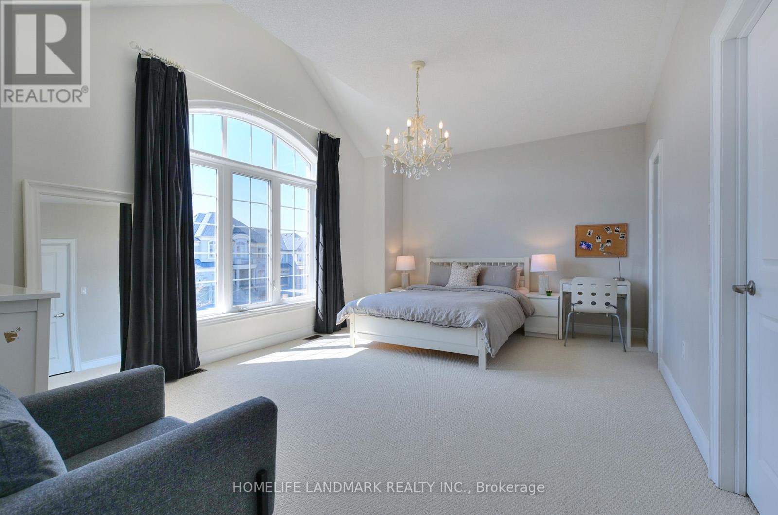 A bedroom with a large bed and a grey couch.