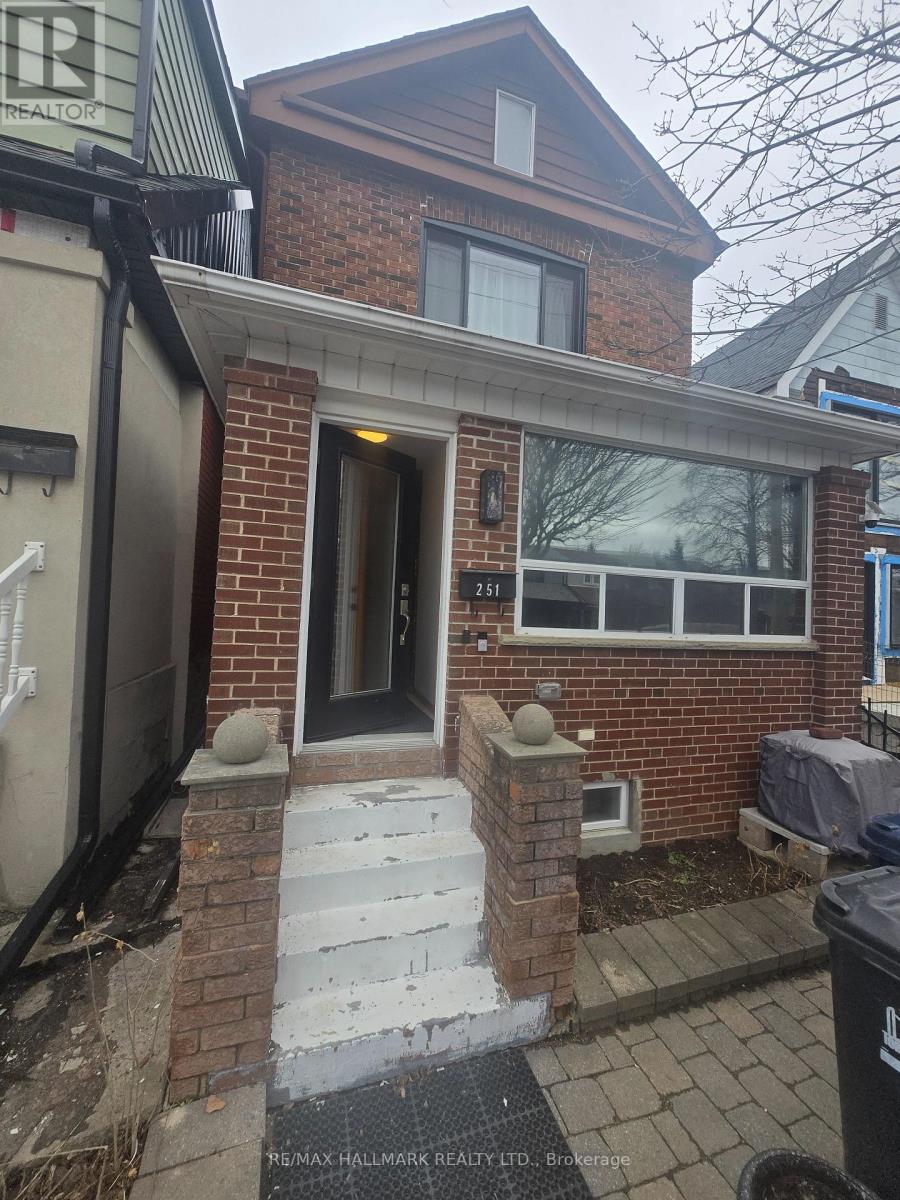 A house with a brown brick facade and a black trash bin in front.