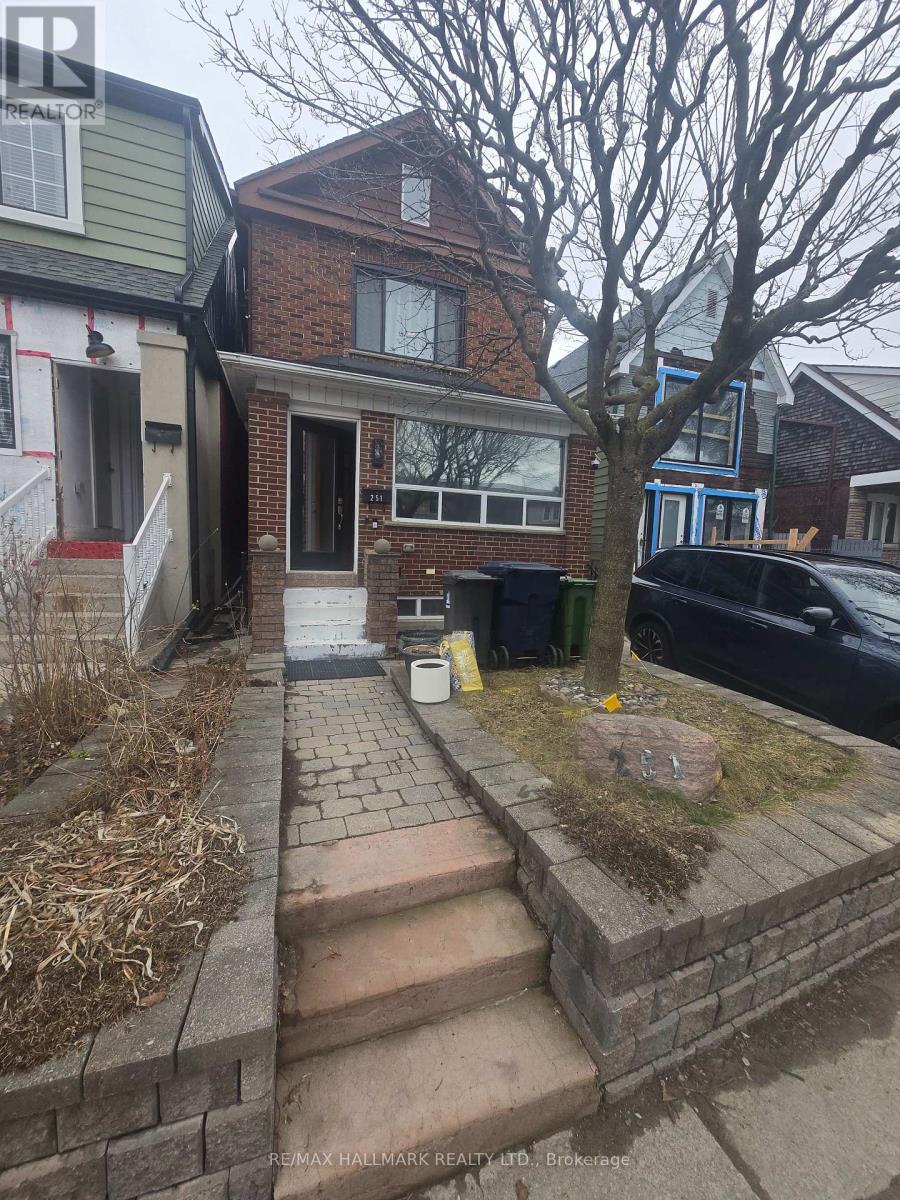 A house with a brick wall and a tree in front.