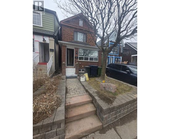 A house with a brick wall and a tree in front.