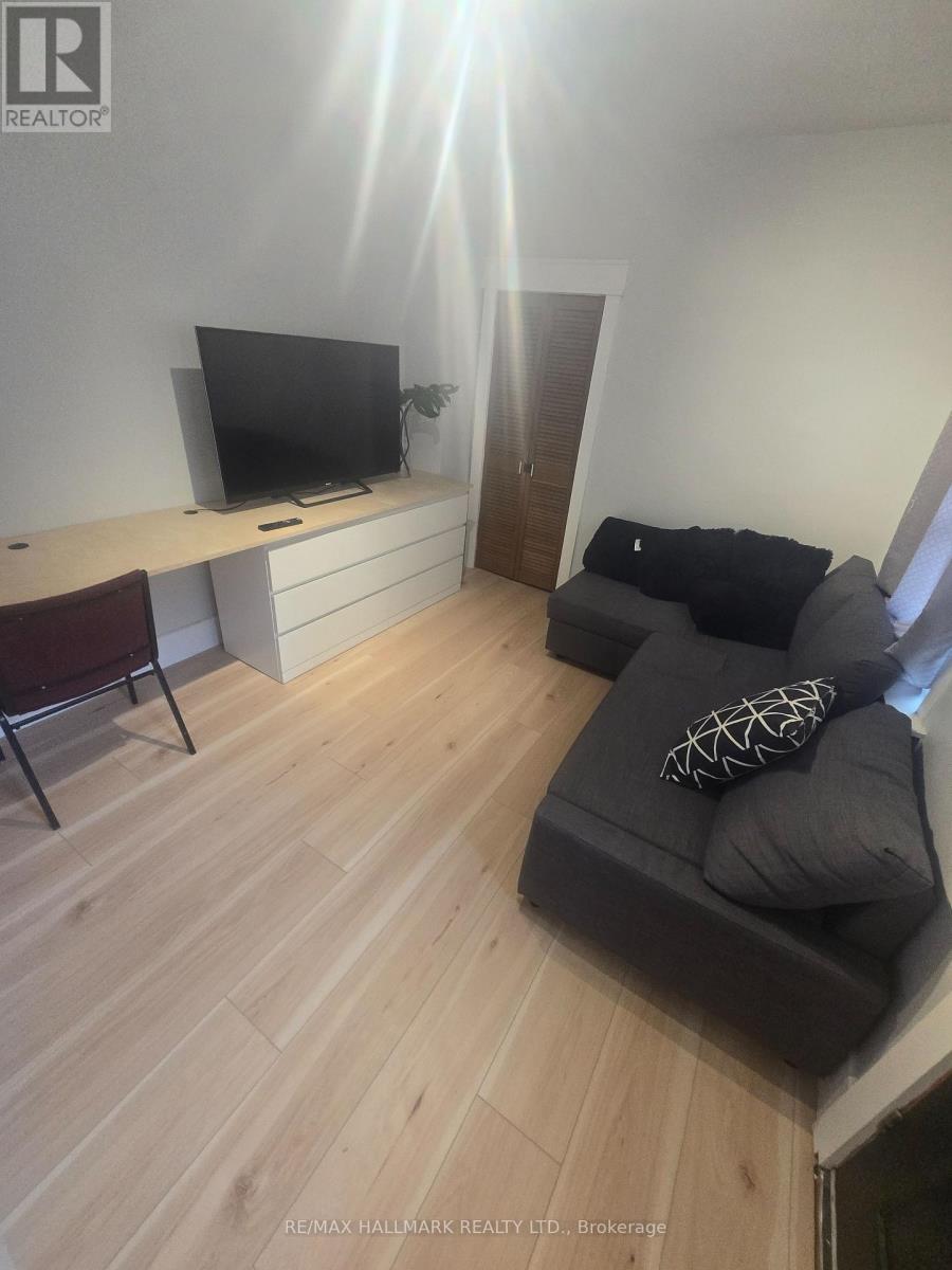 A living room with a grey couch and a television on a white desk.