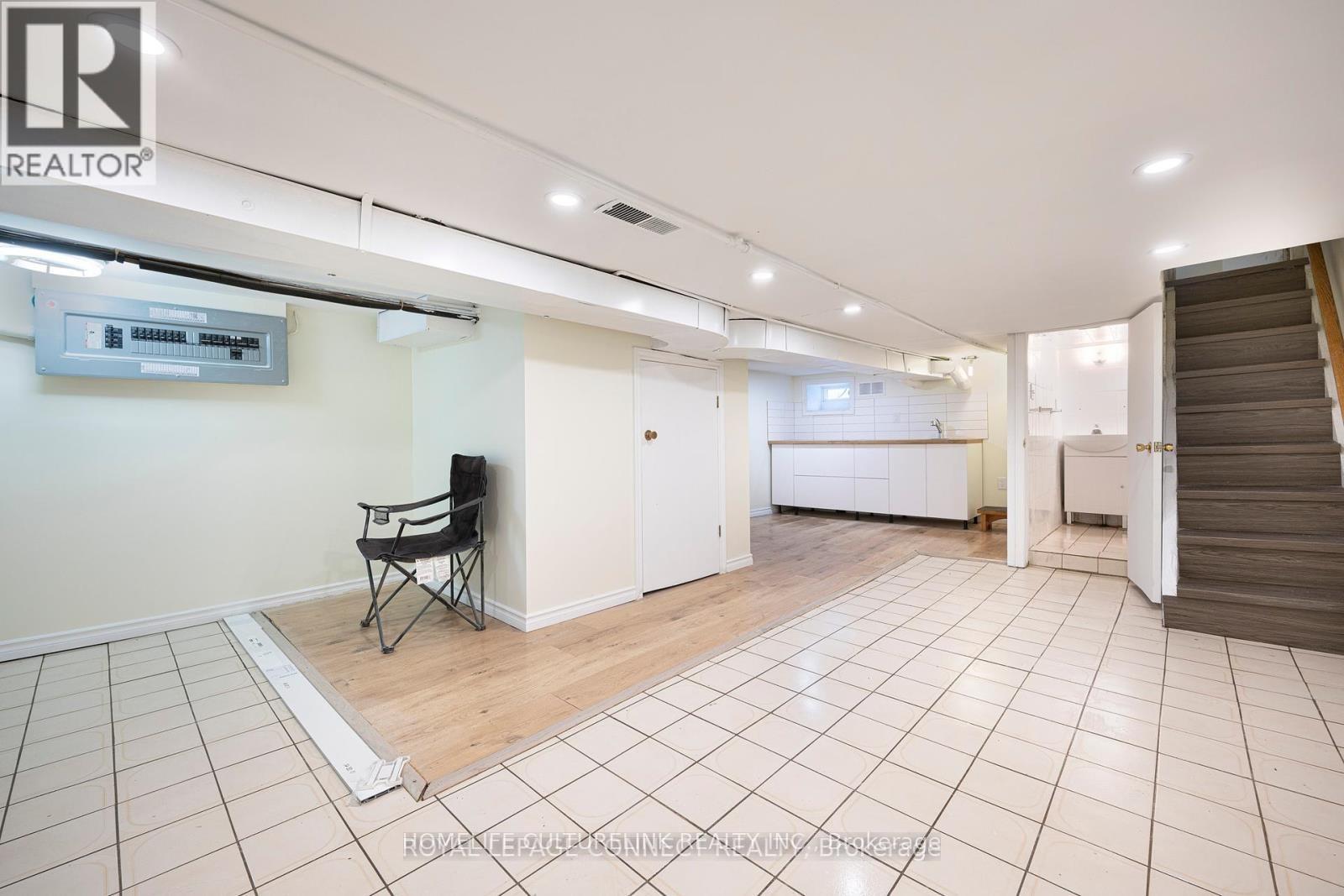 A spacious room with a chair and a television mounted on the wall.