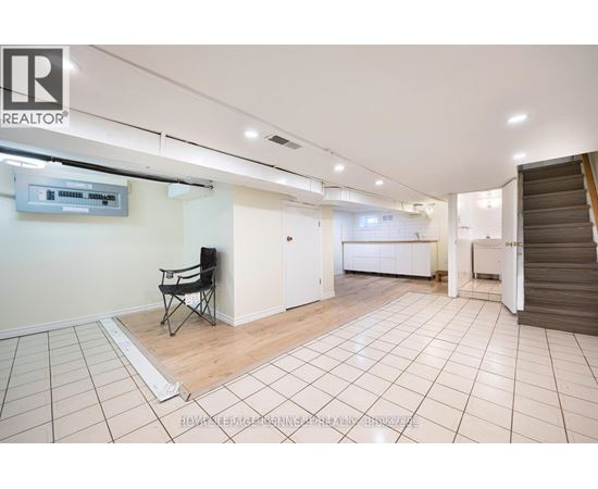 A spacious room with a chair and a television mounted on the wall.