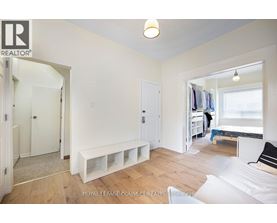 A bedroom with a bed, a bench, and a window.