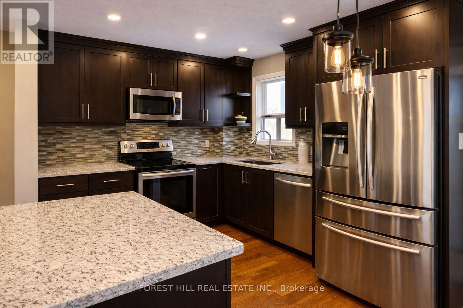 A modern kitchen with a granite countertop and stainless steel appliances.