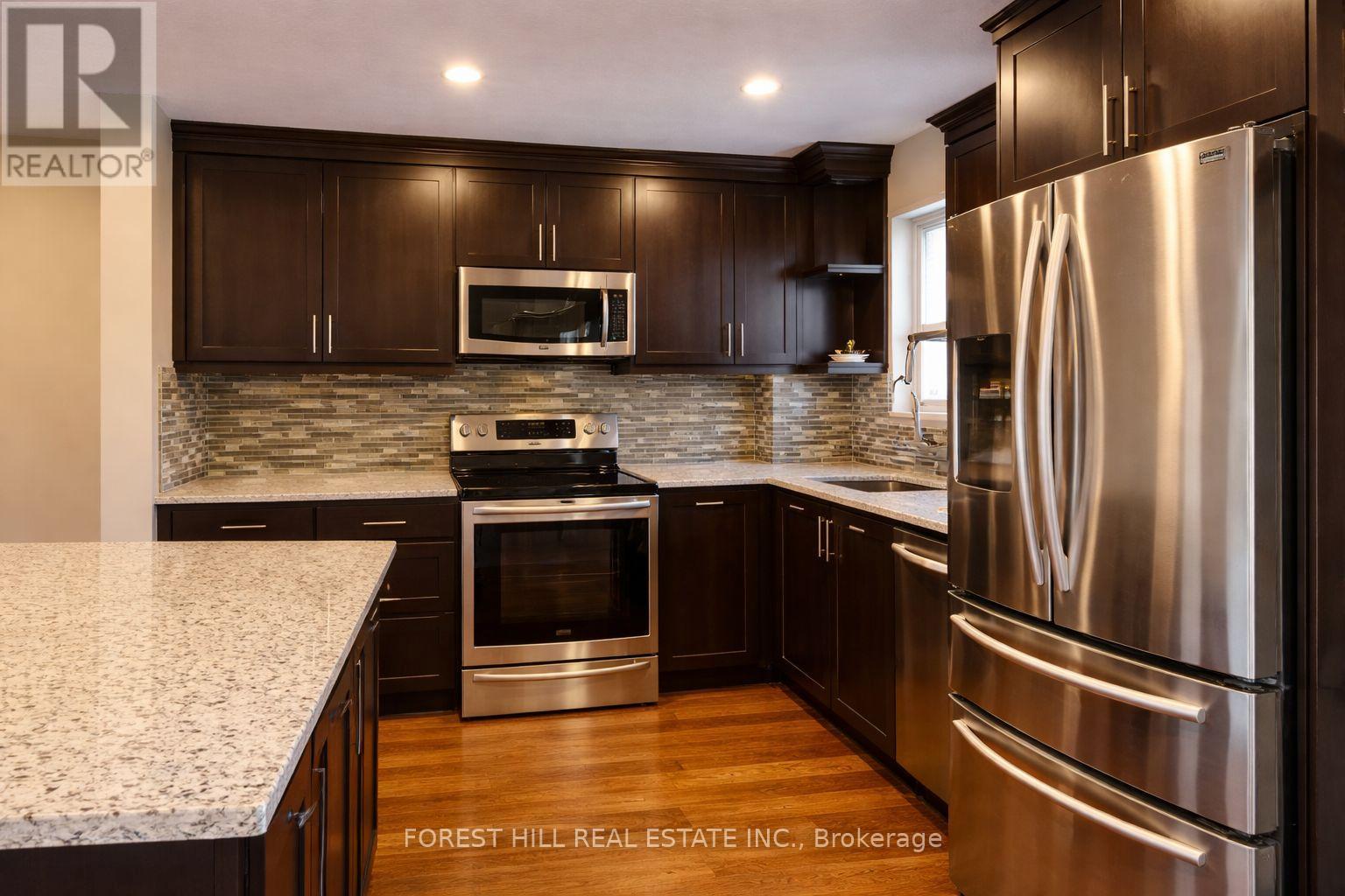 A modern kitchen with dark wood cabinets and stainless steel appliances.
