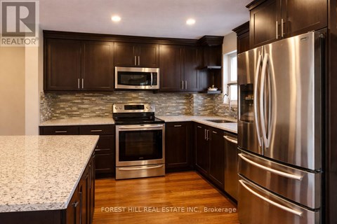 A modern kitchen with dark wood cabinets and stainless steel appliances.