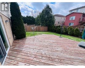 A wooden deck in a backyard with a fence and trees in the background.