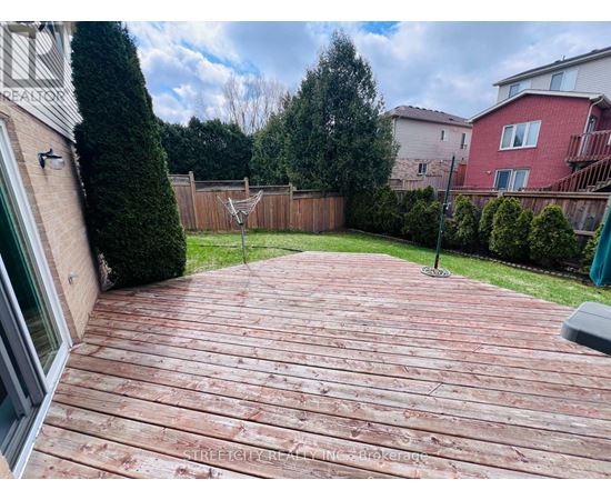 A wooden deck in a backyard with a fence and trees in the background.