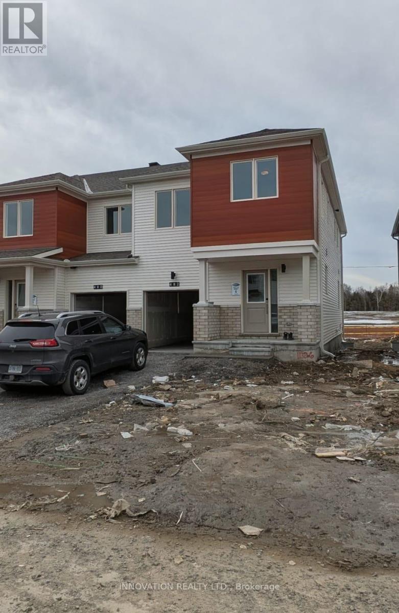 A car is parked in front of a two-story house under construction.