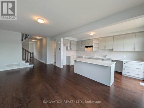 A spacious, well-lit kitchen with white cabinets and a wooden floor.