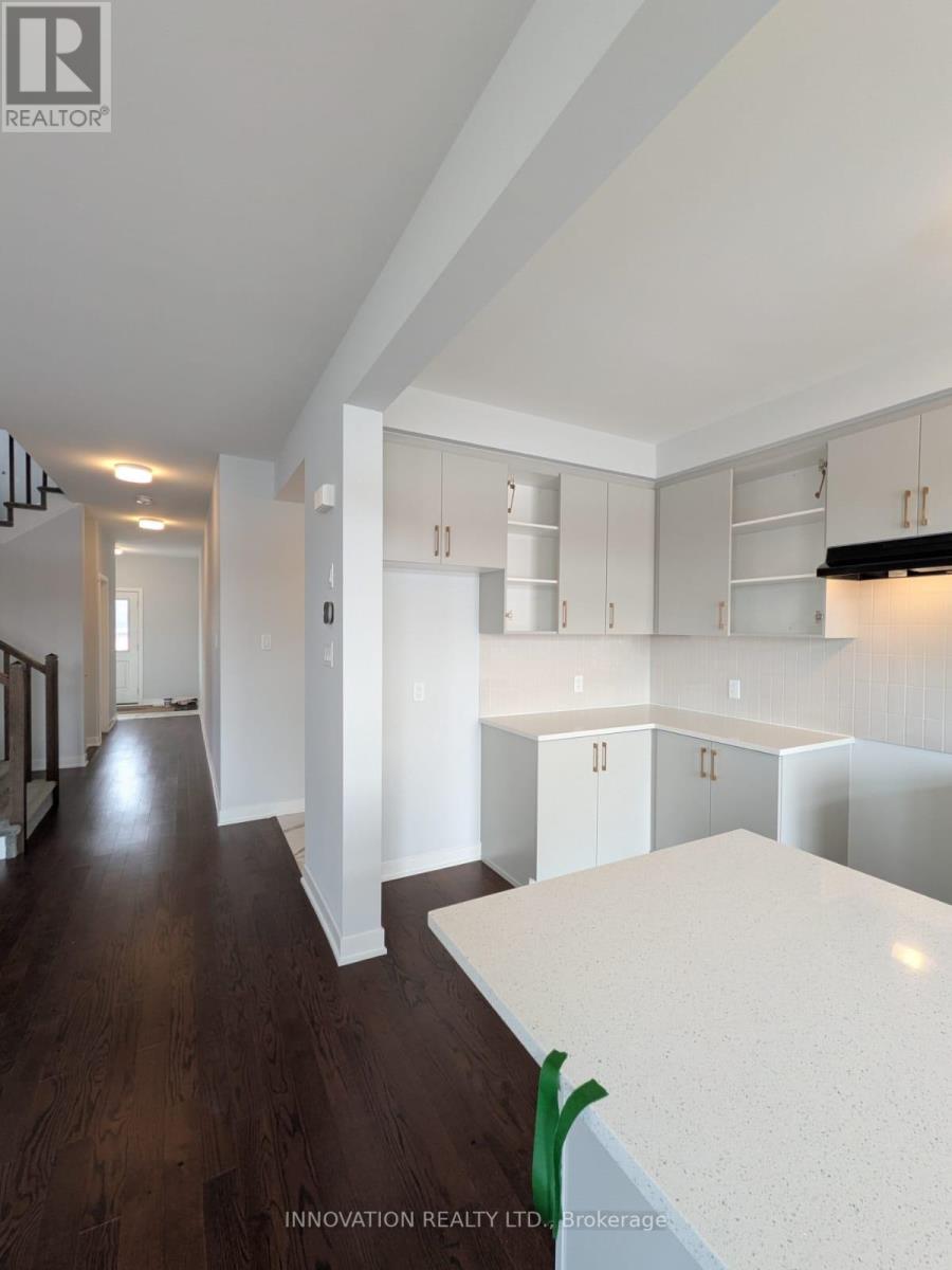 A modern kitchen with white countertops and wooden floors.