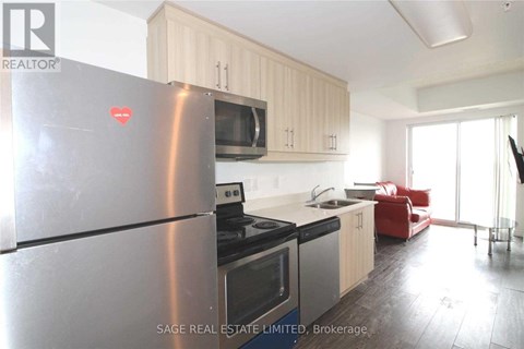 A modern kitchen with a stainless steel refrigerator and a red sofa in the background.