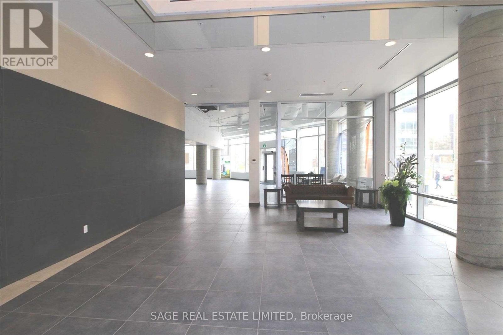 A spacious office lobby with a reception desk and a potted plant.