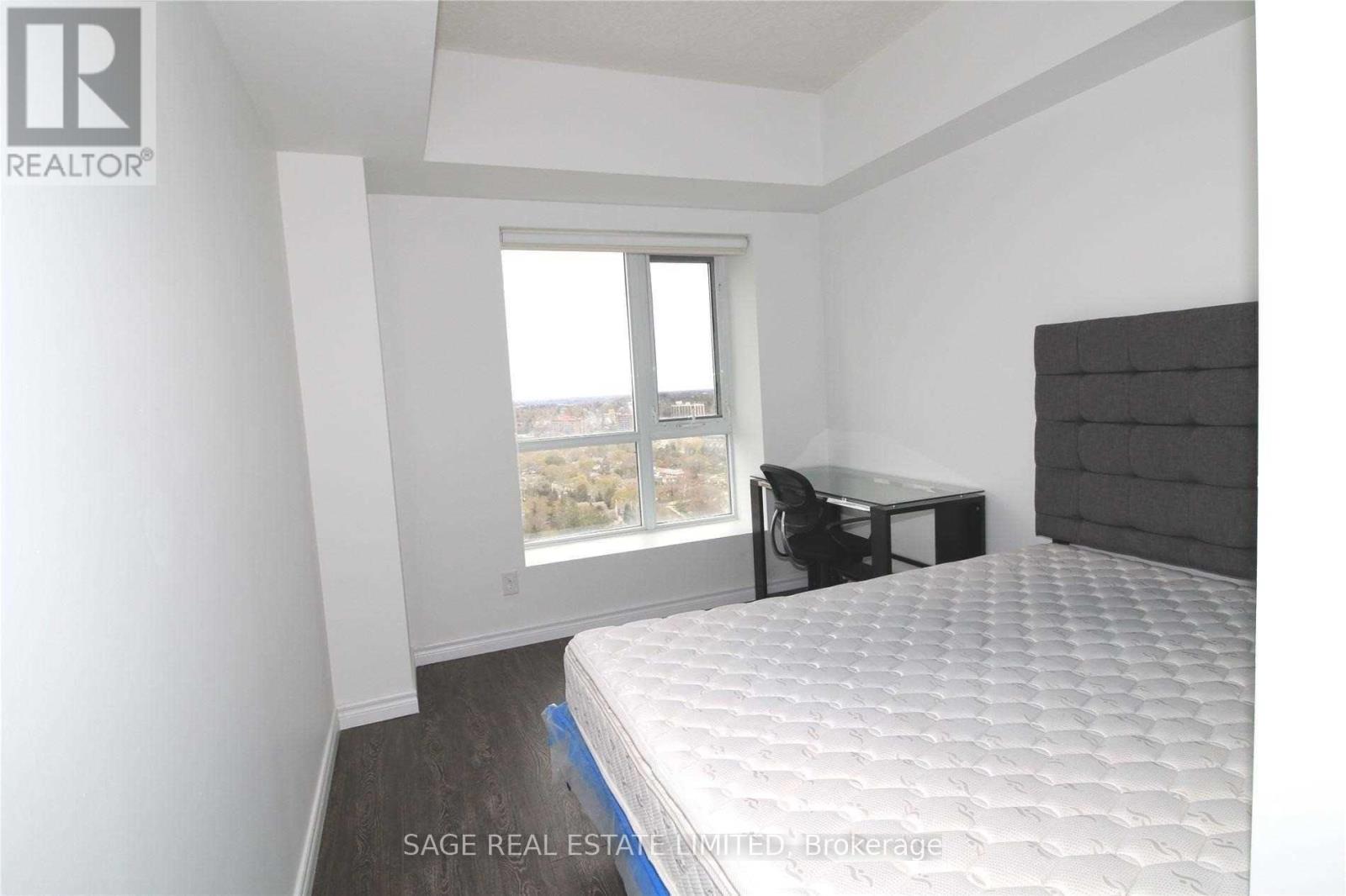 A bedroom with a large bed and a desk with a chair.