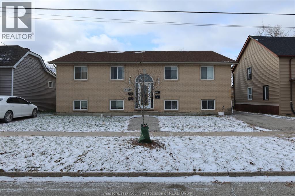 A white car is parked in front of a house with a brown roof.