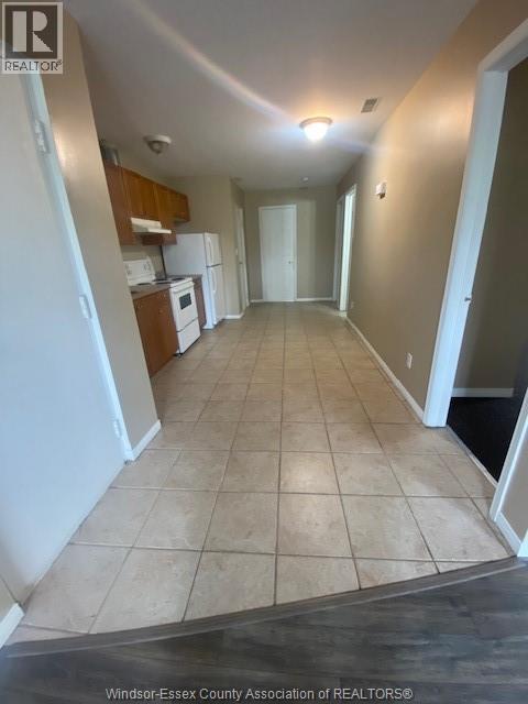 A long hallway with tile flooring and white walls.